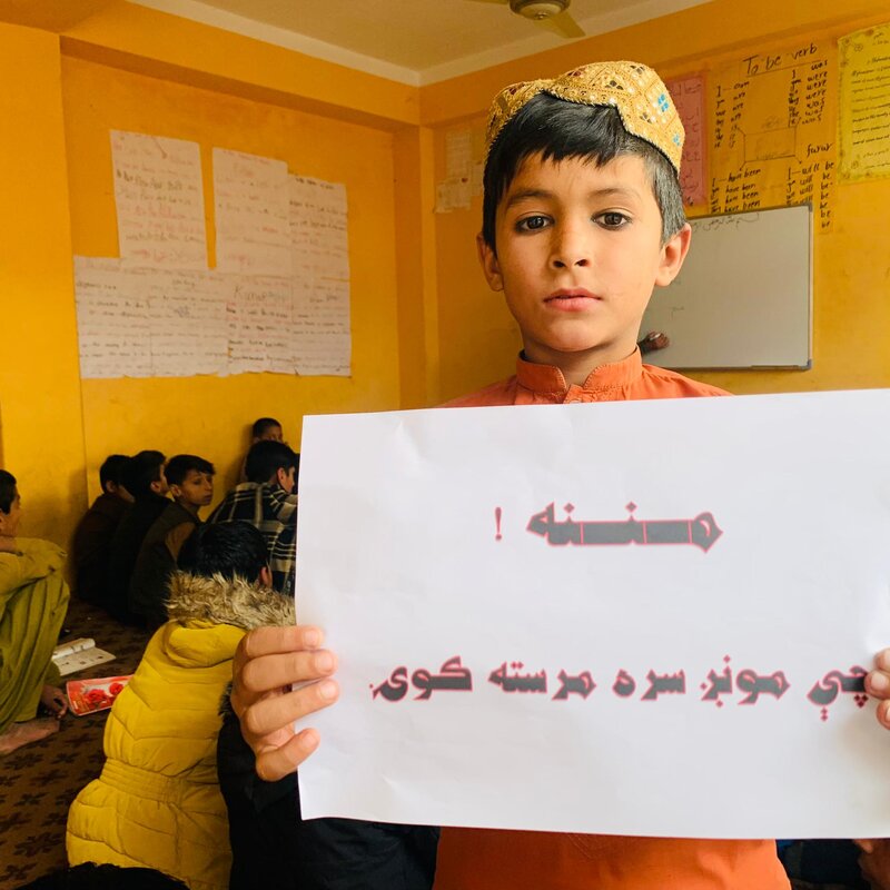 Young student at Zhwand Educational Center holding a thank-you message